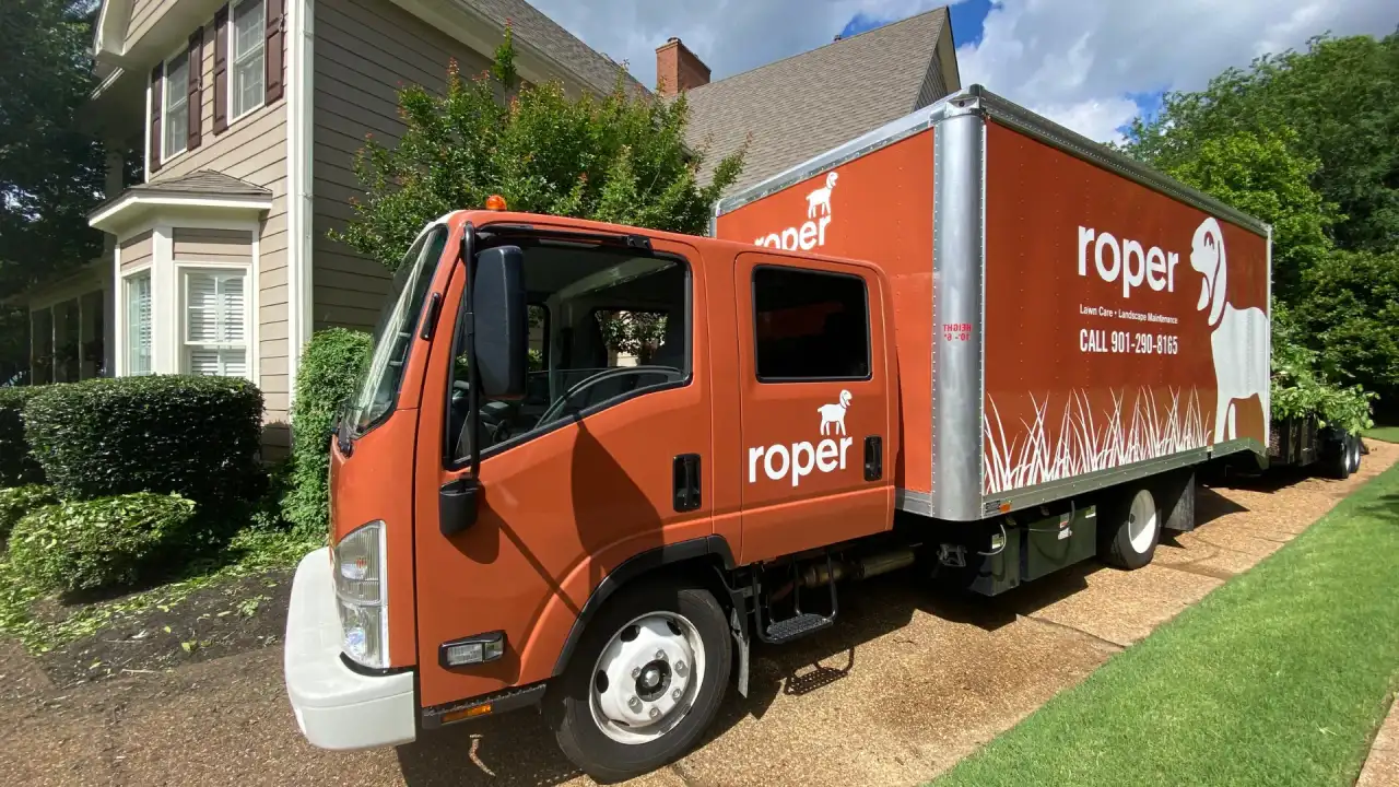 Orange Roper Lawn Care box truck parked in a Memphis residential driveway
